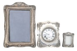 A pocket watch in a silver stand, and two silver photograph frames