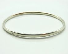 A silver bangle, internal measurement 73mm x 63mm,