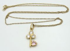 A 9ct gold necklace with key pendant set with pink