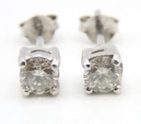A pair of white metal stud earrings set with approx. 1ct of diamond, test electronically as 18ct gol