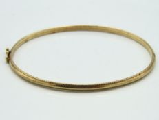 A 9ct gold bangle, internal measurement 60mm x 52m