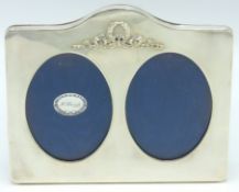 A 1987 London silver double photo frame featuring relief ribbon and reed design with oval apertures