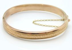 An Edwardian 9ct rose gold bangle with chased deco