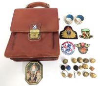 A gentleman's leather bag, a pair of cloisonne napkin rings, a small selection of brass tunic badges