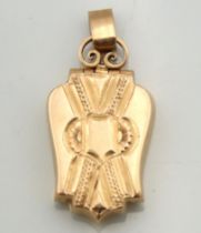 An antique yellow metal locket with ribbon & shield decor, tests electronically as 15ct gold, 32mm