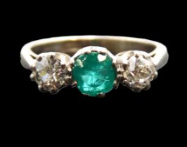 An antique 18ct white gold three stone ring set with a vibrant central emerald, 6.25mm diameter &