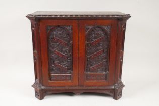 A Gothic Revival oak table top cabinet, with two arched panel doors carved and inscribed 'Praise the