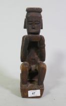 Indonesian tribal carved hardwood figure of a seated male holding a bowl, 29cm high
