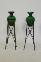 A porcelain of wrought metal and green glass floor vases with tripod supports, 65cm high, chip to