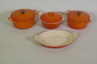 Three Le Creuset casserole dishes with covers and serving dish