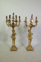 A pair of gilt brass six branch candelabra in the form of putti holding aloft cornucopia, 79cm high