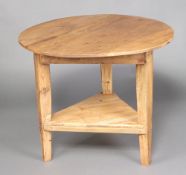 A Victorian circular pine cricket table with triangular shaped undertier, raised on square