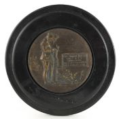 Military interest bronzed memorial plaque housed in a wooden case, 13cm in diameter.