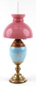 Victorian brass Duplex oil lamp having hand painted porcelain body and pink glass shade, 67cm high.