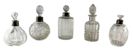 A COLLECTION OF FIVE 20TH CENTURY GLASS SCENT BOTTLES, FOUR WITH SILVER COLLARS