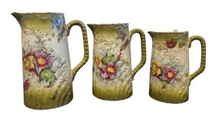 THREE 19TH CENTURY GRADUATING FLORAL CERAMIC JUGS