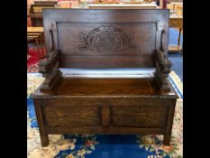 Oak Monks Bench, carved lion arm rests, hinged seat with table top lid.