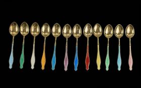 A Boxed Set of 12 Sterling Silver and Enamel Teaspoons of Exquisite Form.