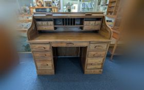 A Golden Oak Roll Top Desk, fitted top with pigeon holes and drawers, above a central drawer with