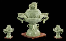 A Carved Light Green Jade Tripod Sensor carved dragon decoration with ring hoops on a wooden