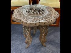 An Antique Carved Burmese Centre Table, with a profusely carved top in deep profile, depicting a