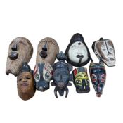 Nine carved polychrome painted African tribal masks, largest height 42cm.