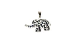 A white metal (stamped 750) and sapphire cluster set pendant, modelled as an elephant, length