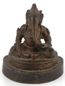 A Javanese bronze figure of Ganesha, probably 14th-15th century, in seated pose, sipping with his