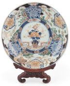 A Japanese Arita porcelain dish, 18th century, painted in Imari palette with a central flower vase