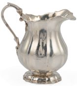 A George IV Irish silver cream jug, Dublin, 1825, of lobed baluster form, with engraved crest,