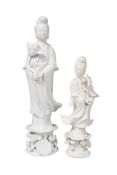 Two Chinese Blanc de Chine Figures of Guanyin, both holding lotus flowers, on floral bases,