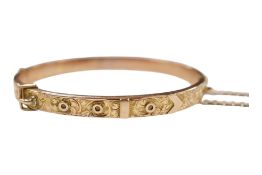 An Edwardian engraved 9ct hinged 'buckle' bangle, with safety chain, 7.5 grams.