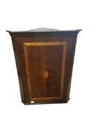 A George III mahogany hanging corner cupboard enclosed by a satinwood banded and chequer inlaid