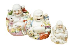 Three mid 20th century Chinese porcelain seated figures of Budai, largest 23cm high