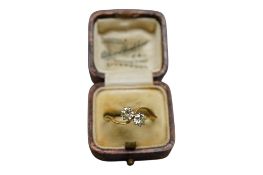A yellow metal and two stone diamond set crossover ring, size O/P, gross weight 2.6 grams.