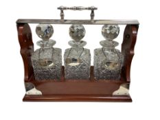 A mahogany and silver-plated tantalus, with three cut glass square decanters and stoppers,