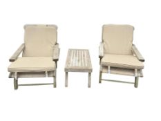 A pair of teak plantation style garden chairs with loose cushion seats, together with a
