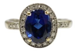 A late 20th century 750 white metal, synthetic sapphire and diamond set oval cluster ring, size N/O,