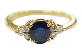 A recent 750 yellow metal and single stone oval cut sapphire ring, with six stone diamond set
