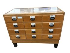 A mid 20th century oak haberdashery counter of twelve drawers, width 119cm, depth 59cm, height 92cm