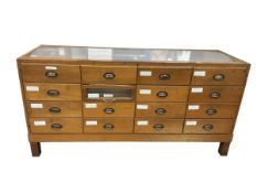 A mid 20th century oak haberdashery counter of sixteen drawers, width 182cm, depth 60cm, height