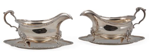 A pair of Elizabeth II silver sauceboats and shaped oval stands by Garrard & Co, with gadrooned