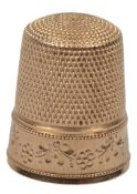 A gold thimble, early 20th century, the base decorated with a floral border, length 2cm, stamped 10,