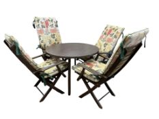 A stained wood conservatory table, diameter 98cm, height 72cm and four folding chairs with cushions