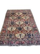 An antique Bakhtiari red ground rug woven with stylized floral and bird motifs, 205 x 142cm
