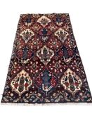 A Bakhtiari red ground rug woven with stylized bird and floral motifs, 217 x 120cm