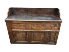 A mid 18th century oak dresser base, fitted with three drawers, over fielded panelled doors, width