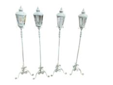 A set of four metal hexagonal garden lanterns on tripod stands, height 155cm