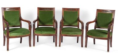 A set of four French Empire walnut fauteuils, each top rail with brass laurel wreath, ribbon and