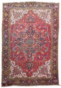A Heriz red ground carpet, woven central lobed medallion within a scattered floral field and wide